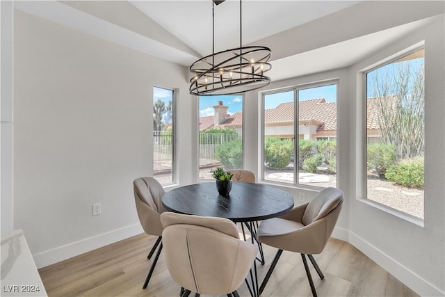 dining room featuring an inviting chandelier, light hardwood / wood-style flooring, a wealth of natural light, and vaulted ceiling