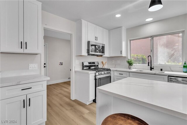 kitchen featuring sink, stainless steel appliances, light stone counters, light hardwood / wood-style flooring, and white cabinets