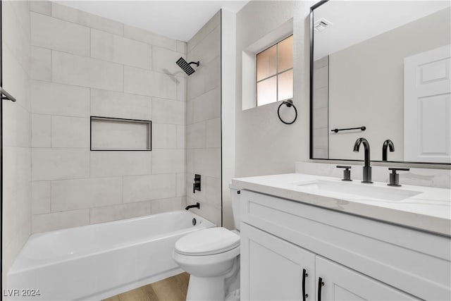 full bathroom featuring vanity, tiled shower / bath combo, hardwood / wood-style flooring, and toilet