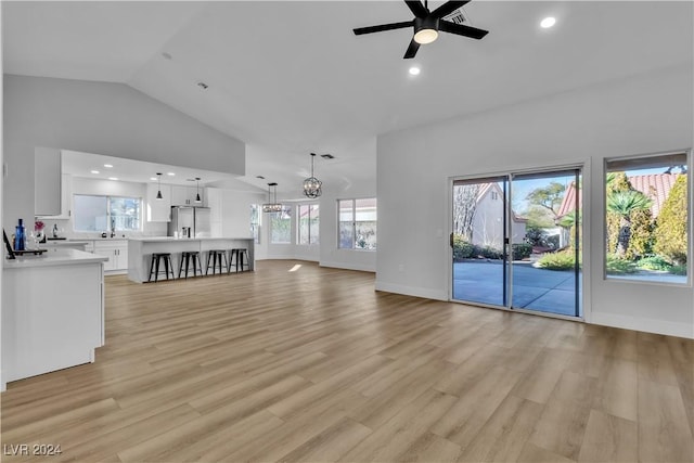 unfurnished living room featuring high vaulted ceiling, light hardwood / wood-style flooring, and ceiling fan