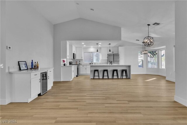 kitchen featuring white cabinetry, beverage cooler, vaulted ceiling, and appliances with stainless steel finishes