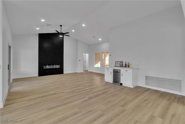 unfurnished living room featuring high vaulted ceiling, ceiling fan, wine cooler, and light hardwood / wood-style flooring