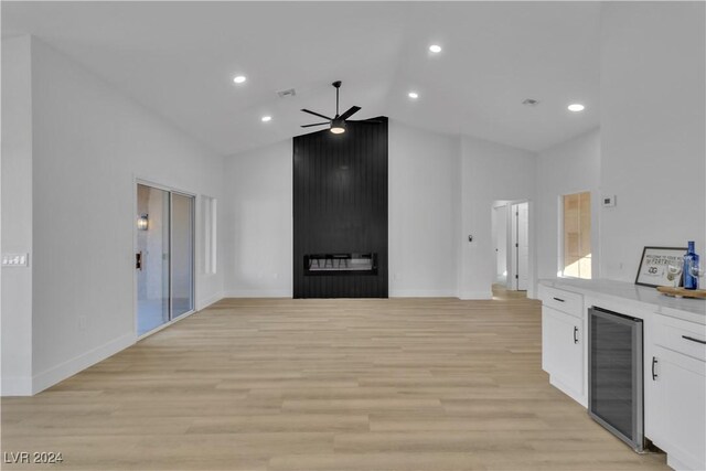 kitchen with high vaulted ceiling, white cabinets, ceiling fan, light wood-type flooring, and beverage cooler