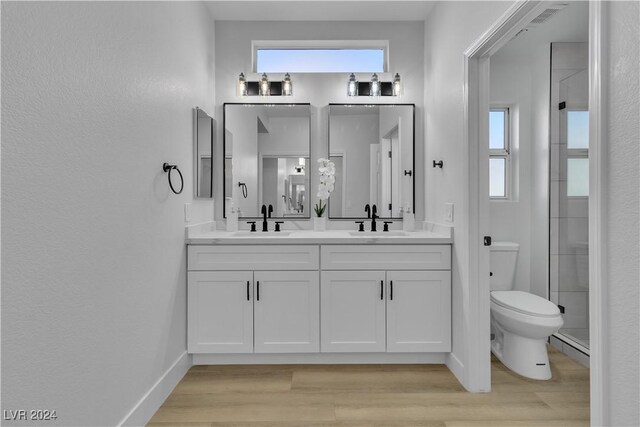 bathroom featuring hardwood / wood-style floors, vanity, toilet, and walk in shower