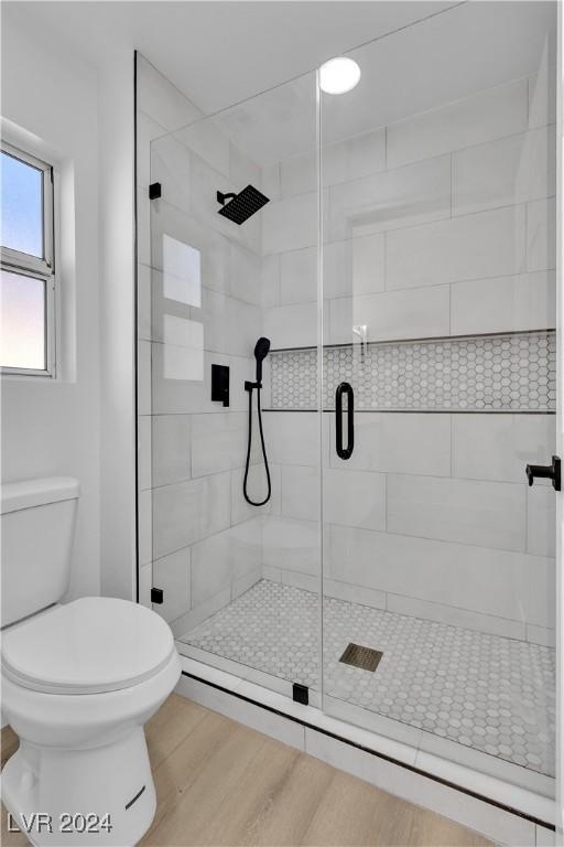 bathroom featuring hardwood / wood-style flooring, toilet, and walk in shower