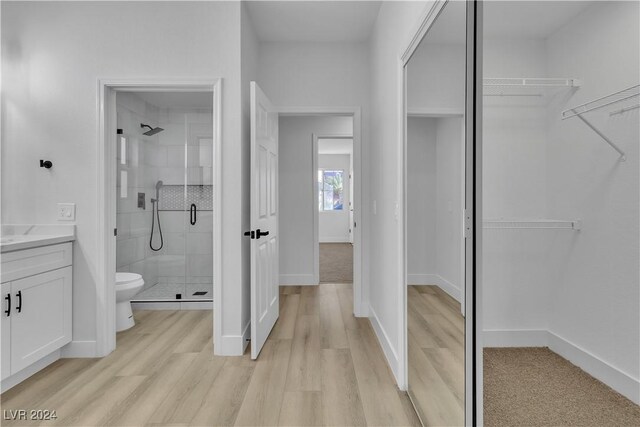 bathroom featuring a shower with door, vanity, hardwood / wood-style floors, and toilet