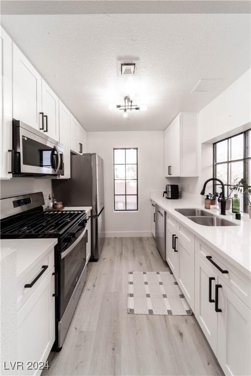 4724 Nara Vista Way Unit 204, Las Vegas, NV 89103 - kitchen featuring appliances with stainless steel finishes, a sink, light wood-type flooring, white cabinets, and light countertops