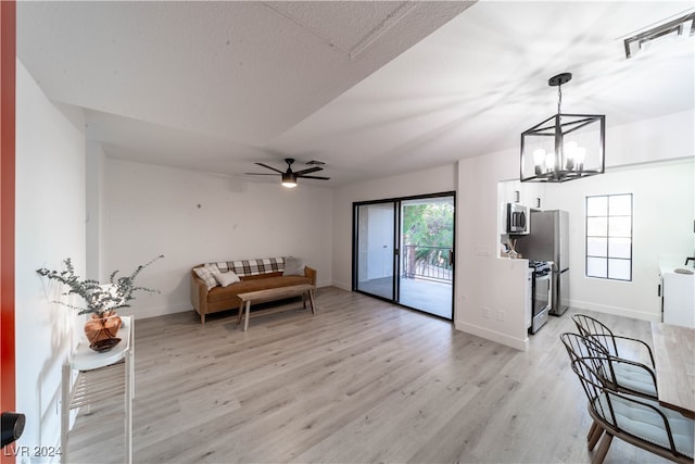 sitting room featuring ceiling fan with notable chandelier and light wood-type flooring