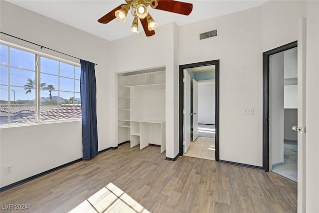 unfurnished bedroom with light wood-type flooring, ceiling fan, and a closet