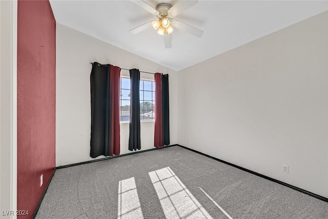 carpeted spare room featuring vaulted ceiling and ceiling fan