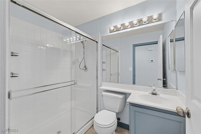 bathroom featuring toilet, vanity, and a shower with shower door