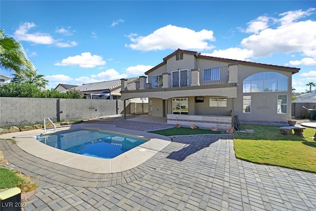 rear view of property featuring a fenced in pool, a balcony, and a patio area