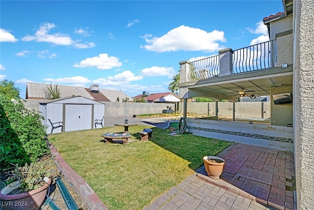 view of yard featuring a storage unit, ceiling fan, a balcony, and a patio area