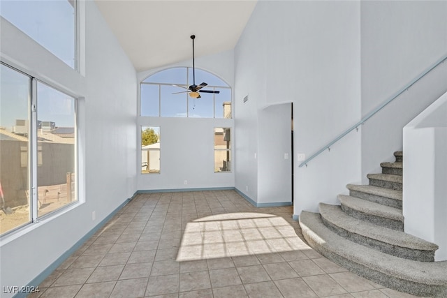 interior space with light tile patterned flooring, ceiling fan, and high vaulted ceiling