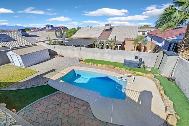 view of swimming pool featuring a patio area and a shed