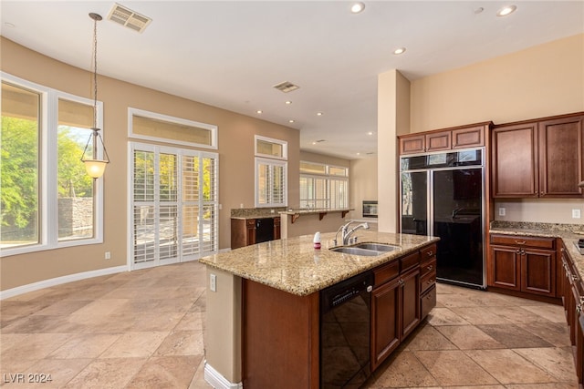 kitchen featuring built in fridge, a center island with sink, dishwasher, sink, and decorative light fixtures