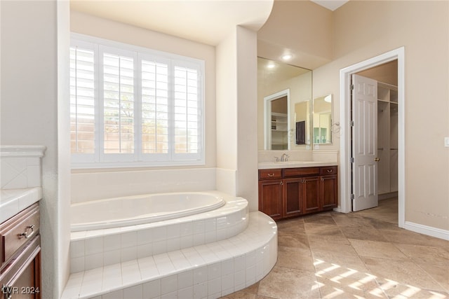 bathroom with tiled bath, vanity, and tile patterned floors