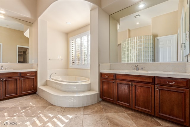 bathroom featuring tasteful backsplash, vanity, tile patterned floors, and tiled tub