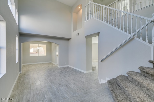 interior space featuring hardwood / wood-style floors, a towering ceiling, and a chandelier