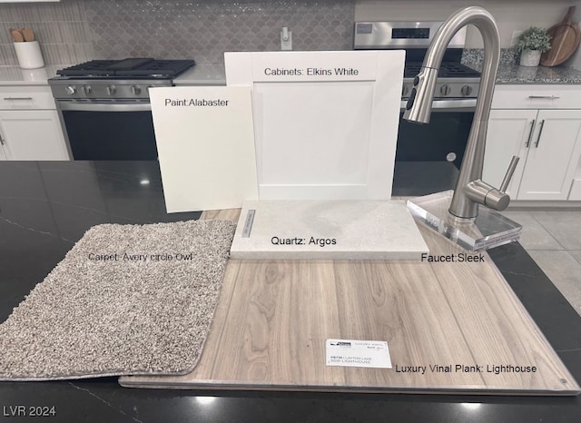 interior details with white cabinets, backsplash, light stone counters, and stainless steel range with gas stovetop