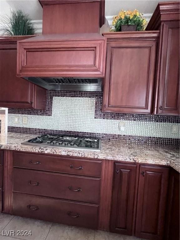 kitchen featuring stainless steel gas stovetop, light tile patterned flooring, light stone countertops, and tasteful backsplash