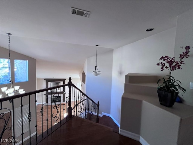 stairway featuring a chandelier, wood-type flooring, and lofted ceiling