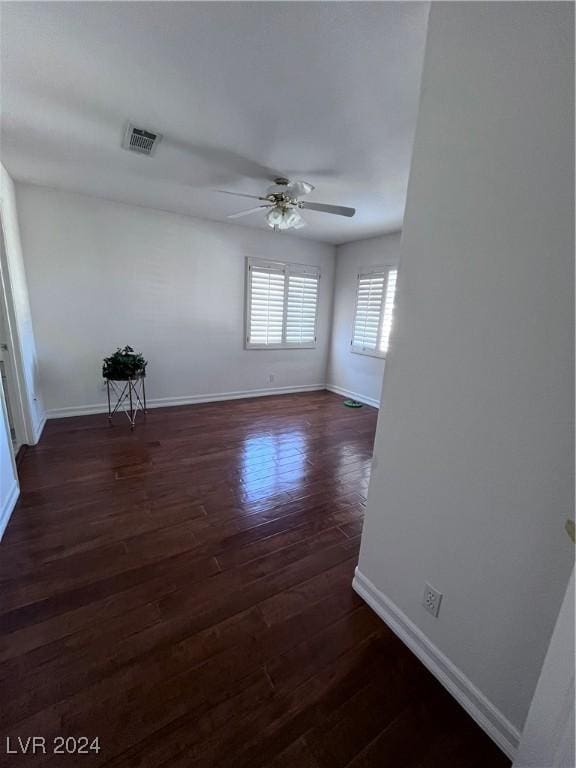 empty room with ceiling fan and dark hardwood / wood-style flooring