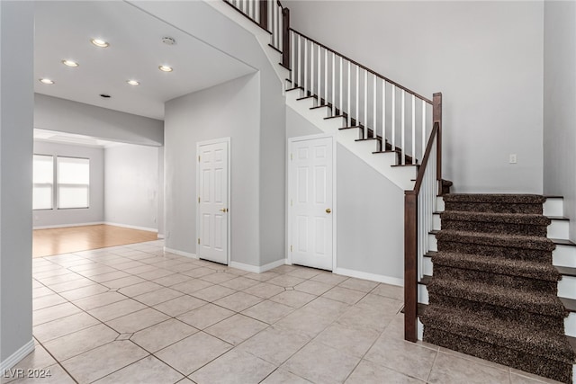 stairs featuring a towering ceiling and tile patterned floors