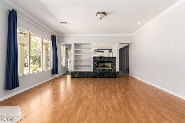 unfurnished living room featuring hardwood / wood-style floors, a high end fireplace, ceiling fan, and crown molding