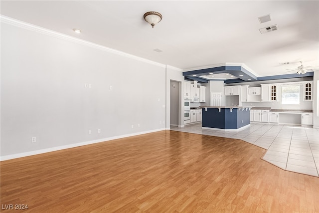 unfurnished living room featuring ceiling fan, ornamental molding, and light hardwood / wood-style flooring