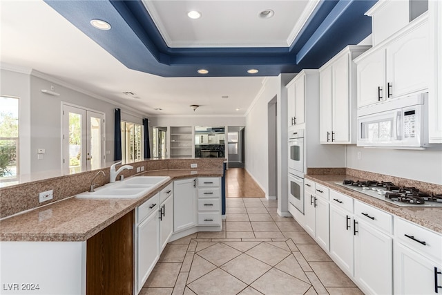 kitchen with sink, an island with sink, white appliances, crown molding, and white cabinets