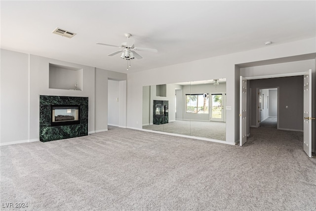 unfurnished living room with carpet flooring, ceiling fan, and a high end fireplace