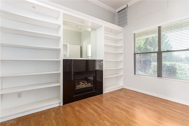 unfurnished living room with wood-type flooring and ornamental molding