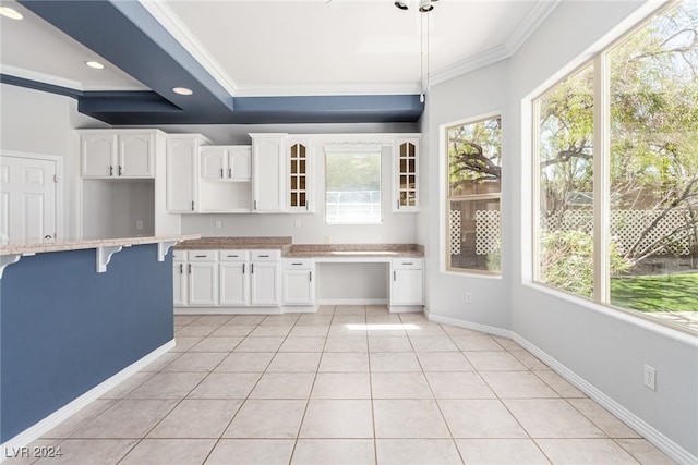 kitchen with white cabinets, a kitchen bar, a healthy amount of sunlight, and crown molding