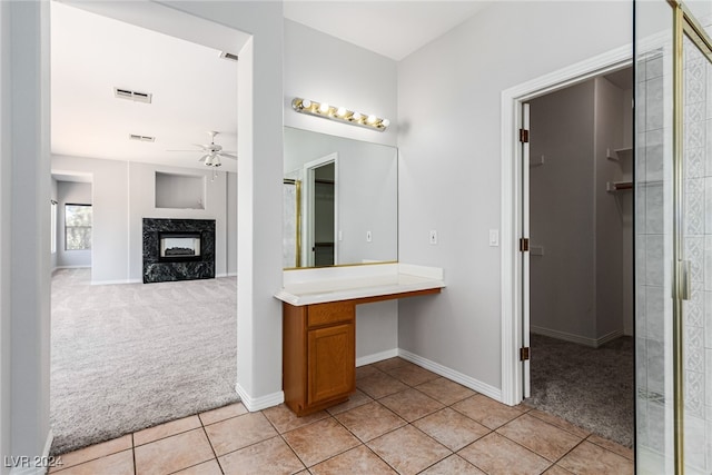 bathroom with tile patterned flooring, a premium fireplace, vanity, ceiling fan, and walk in shower