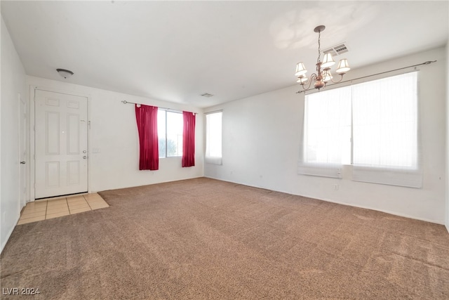 carpeted empty room featuring a notable chandelier