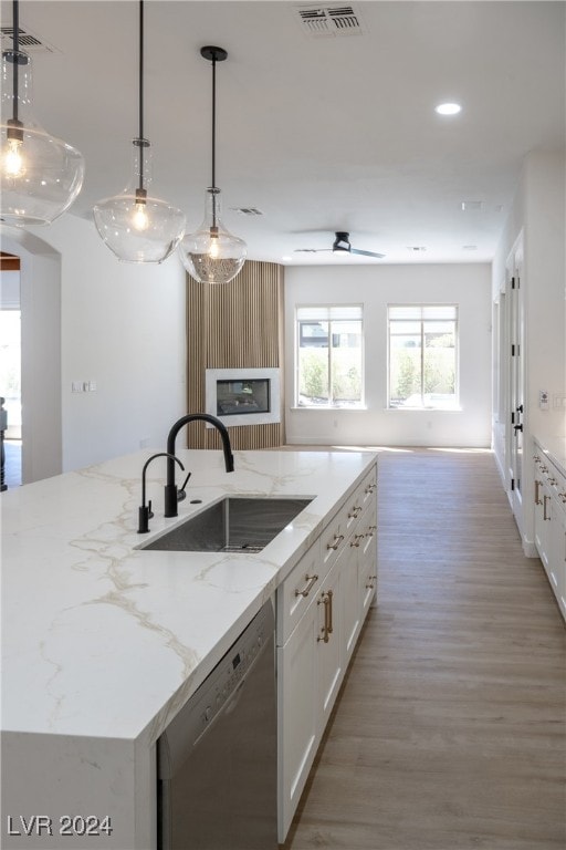 kitchen featuring dishwasher, sink, white cabinets, and decorative light fixtures