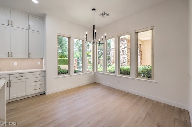 unfurnished dining area with a chandelier and light hardwood / wood-style floors