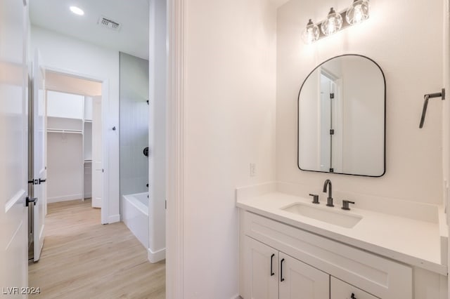 bathroom with hardwood / wood-style floors, vanity, and shower / bath combination