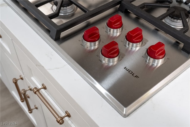 interior details featuring stainless steel cooktop and white cabinets