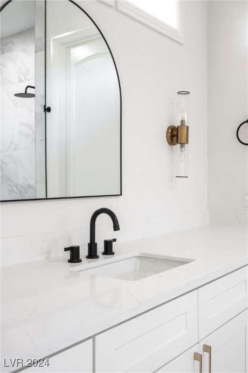 bathroom featuring tiled shower and vanity