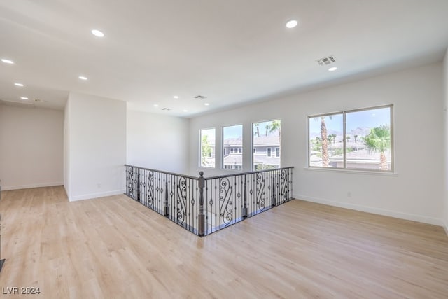 empty room with a wealth of natural light and light hardwood / wood-style flooring