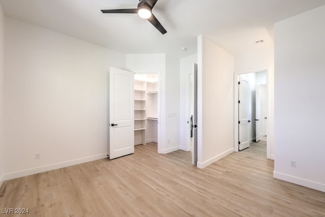 unfurnished bedroom featuring a walk in closet, ensuite bath, ceiling fan, light hardwood / wood-style floors, and a closet