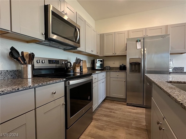 kitchen featuring stone countertops, light hardwood / wood-style flooring, and appliances with stainless steel finishes