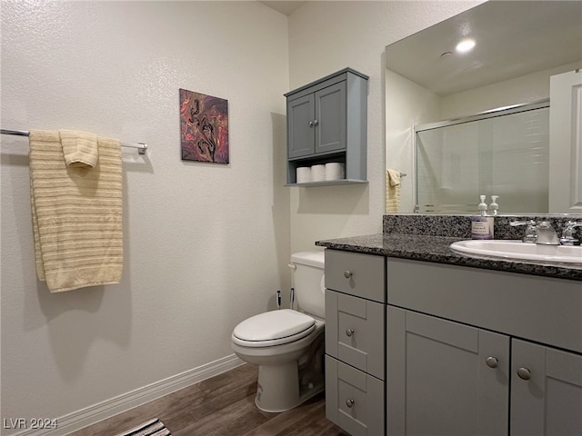 bathroom with toilet, vanity, an enclosed shower, and hardwood / wood-style floors