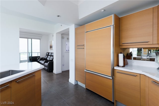 kitchen featuring paneled fridge, a healthy amount of sunlight, and dark tile patterned flooring