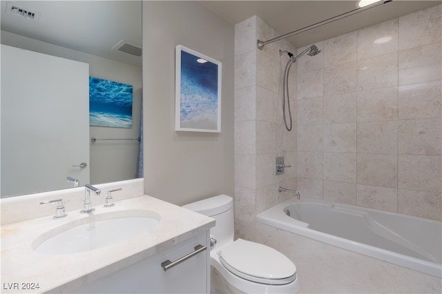 full bathroom featuring tiled shower / bath, vanity, and toilet