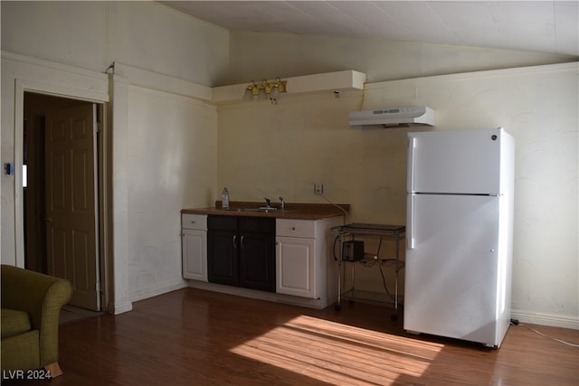 kitchen featuring dark wood-type flooring, white cabinetry, vaulted ceiling, and white fridge