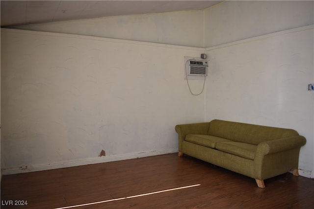 unfurnished room featuring dark hardwood / wood-style flooring, lofted ceiling, and a wall mounted air conditioner