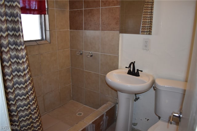 bathroom featuring toilet and a tile shower